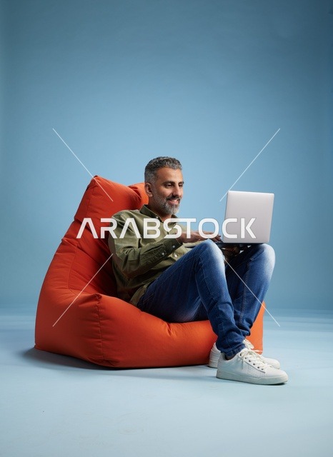 رجل سعودي يعمل على لابتوب في كرسي بين باج