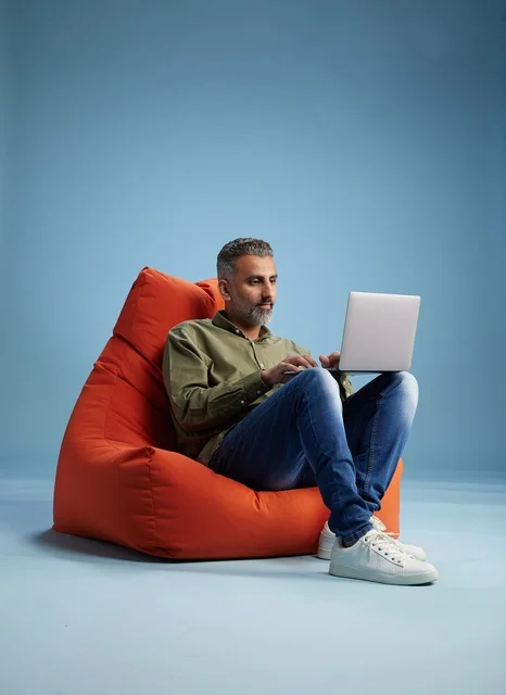 Saudi Man Working on Laptop on Orange Beanbag