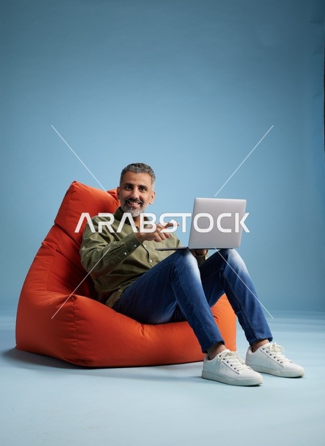Saudi Man Using Laptop on Orange Bean Bag
