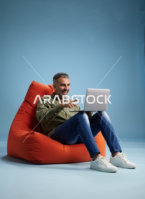 Saudi Man Using Laptop on Orange Bean Bag