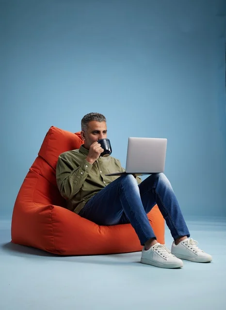 Saudi Man Working on Laptop on Red Bean Bag