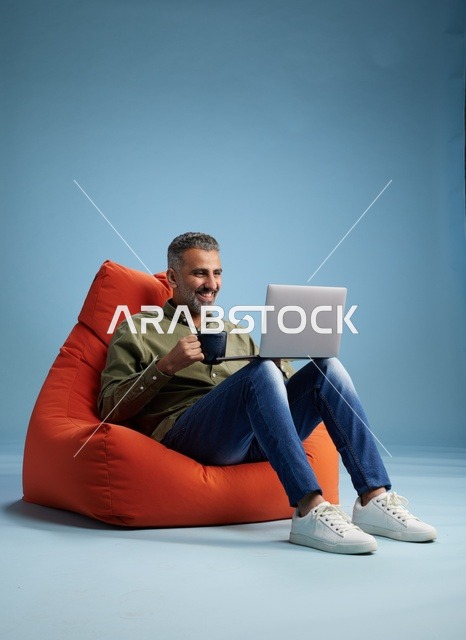 Saudi Man Using Laptop on Orange Beanbag