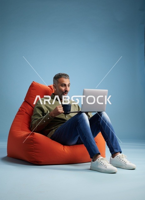 رجل سعودي يعمل على كمبيوتر محمول على كرسي بين باج