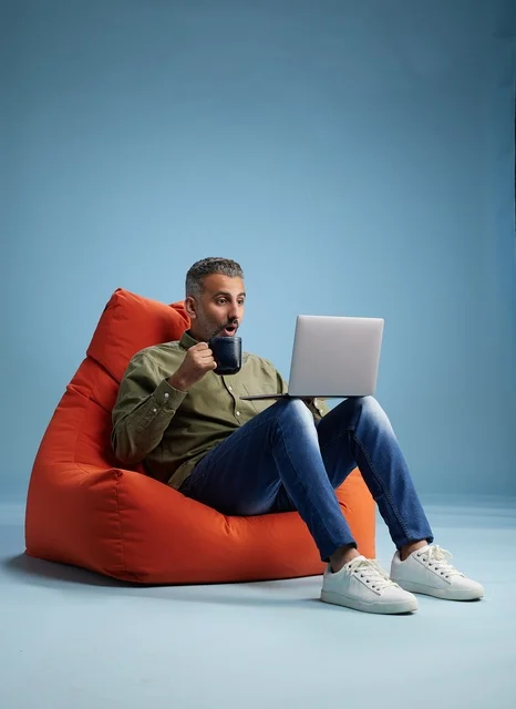 Saudi Man Using Laptop on Orange Beanbag Studio