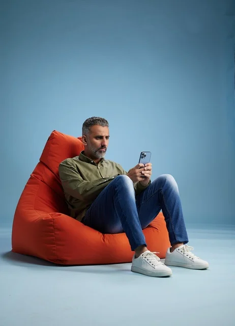 Saudi Man Using Smartphone on Red Bean Bag Chair