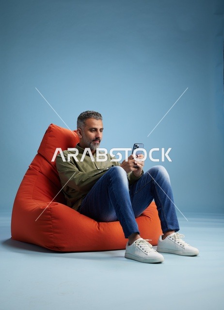 Saudi Man Using Smartphone on Orange Beanbag