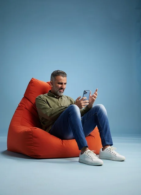 Focused Saudi Man Using Smartphone on Orange Bean Bag