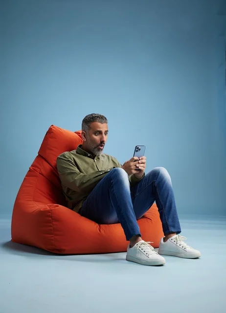 Surprised Saudi Man on Beanbag Using Smartphone