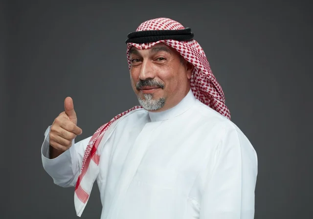 رجل سعودي بالزي التقليدي يشير بالإبهام للأعلى