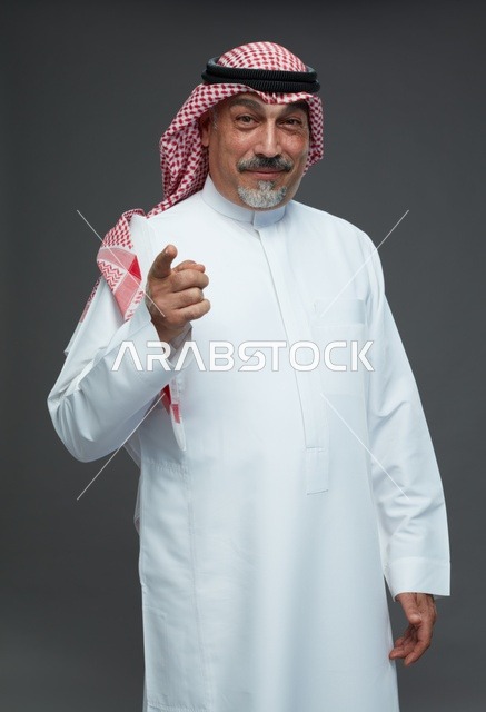 رجل سعودي بالزي التقليدي يشير نحو الكاميرا