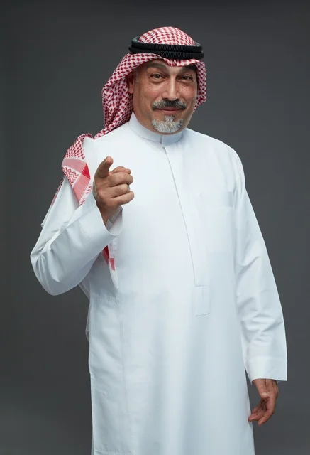 رجل سعودي بالزي التقليدي يشير نحو الكاميرا