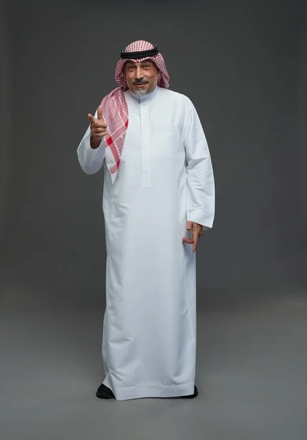 رجل سعودي بالزي التقليدي يشير للكاميرا في الاستوديو