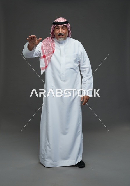 رجل سعودي بالزي التقليدي يؤدي إيماءة باليد في استوديو