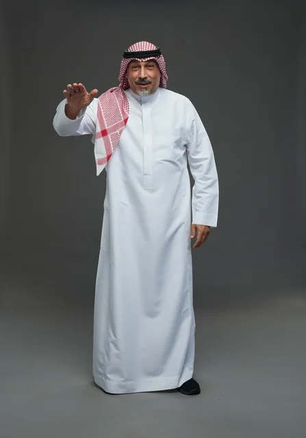 رجل سعودي بالزي التقليدي يؤدي إيماءة باليد في استوديو