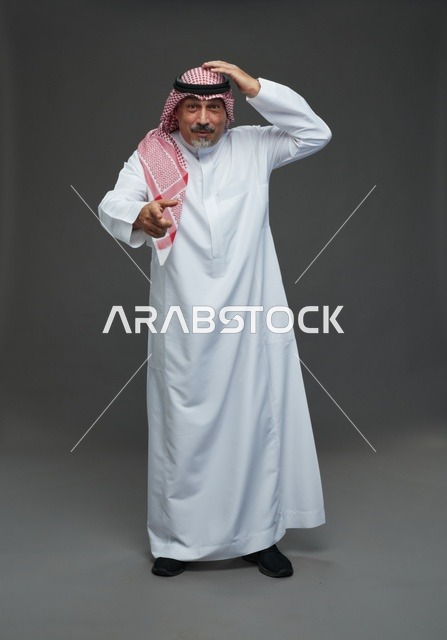 رجل سعودي بالزي التقليدي يشير للأمام بتعبير وجه حائر