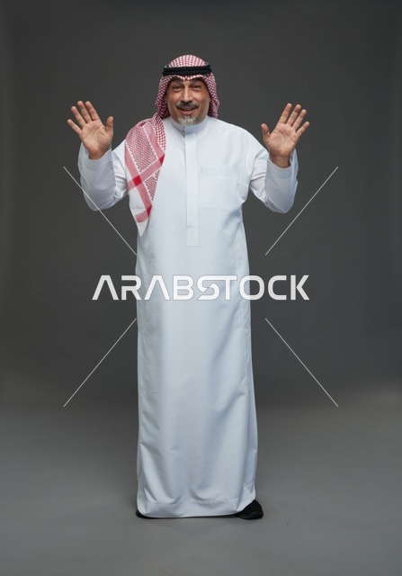 رجل سعودي بالزي التقليدي يرفع يديه للأعلى