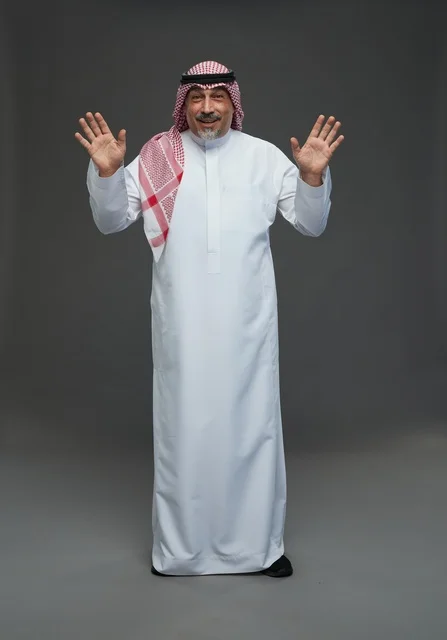رجل سعودي بالزي التقليدي يرفع يديه للأعلى