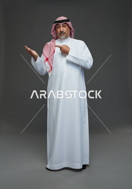 رجل سعودي بالزي التقليدي يشير بيده للعرض
