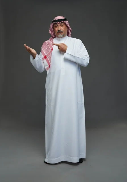 رجل سعودي بالزي التقليدي يشير بيده للعرض