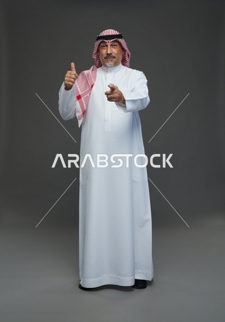 رجل سعودي بالثوب والشماغ يشير بيده في استوديو