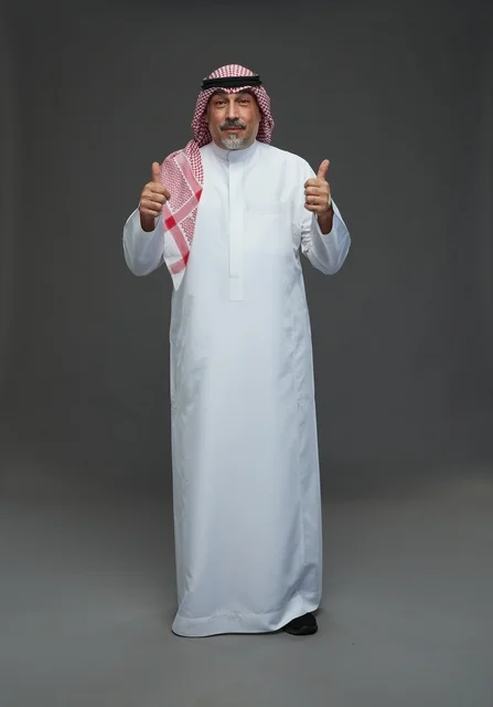 رجل سعودي بالزي التقليدي يرفع إبهامه علامة على الموافقة