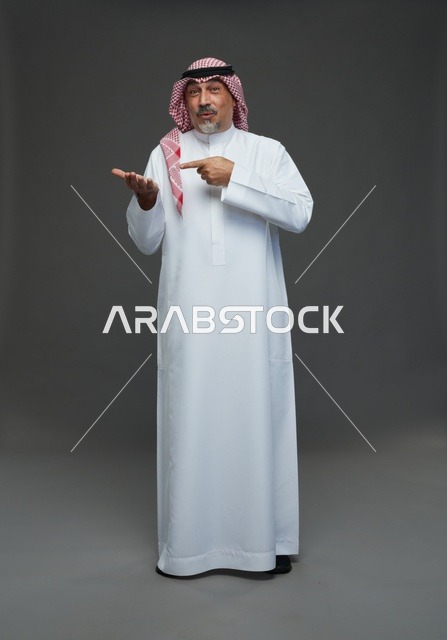 رجل سعودي بالزي التقليدي يشير بيده في الاستوديو