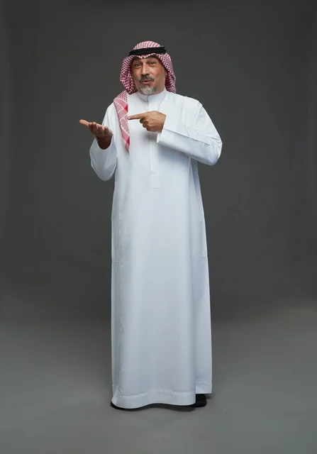 رجل سعودي بالزي التقليدي يشير بيده في الاستوديو