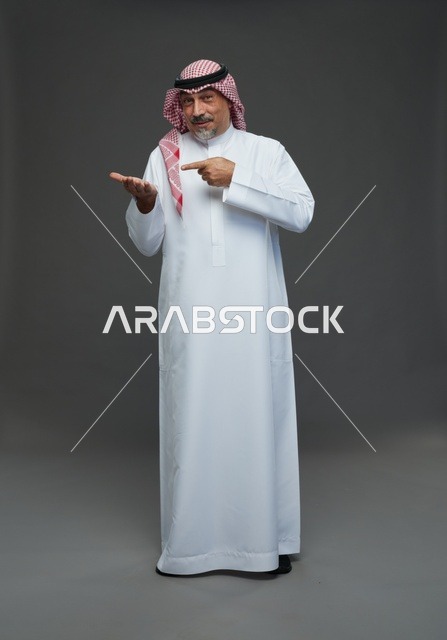 رجل سعودي بالزي التقليدي يشير إلى يده