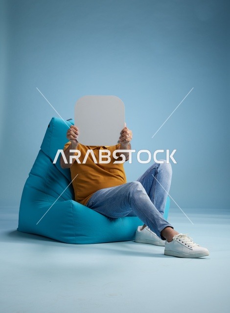 رجل سعودي يحمل لوحة فارغة على مقعد محشو