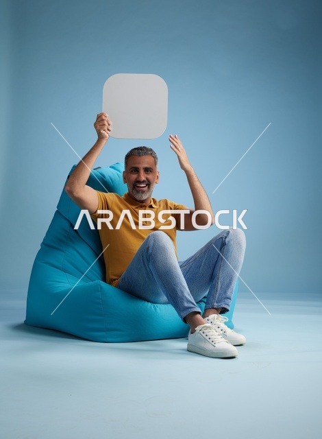 رجل سعودي يحمل لوحة موك أب فارغة على خلفية زرقاء