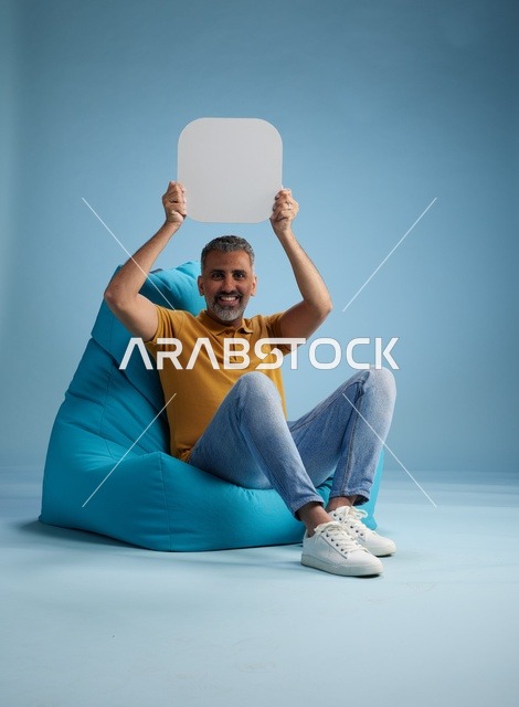 رجل سعودي يحمل لوحة موك أب فارغة على كرسي