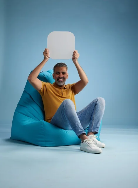 رجل سعودي يحمل لوحة موك أب فارغة على كرسي