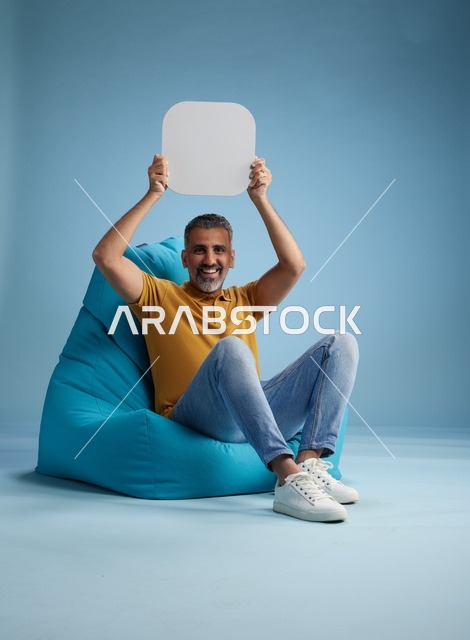 رجل سعودي يحمل لوحة موك أب فارغة بخلفية زرقاء