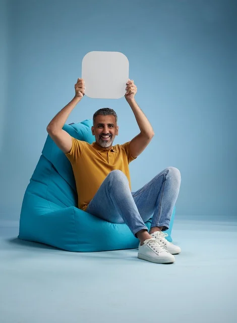 رجل سعودي يحمل لوحة موك أب فارغة بخلفية زرقاء