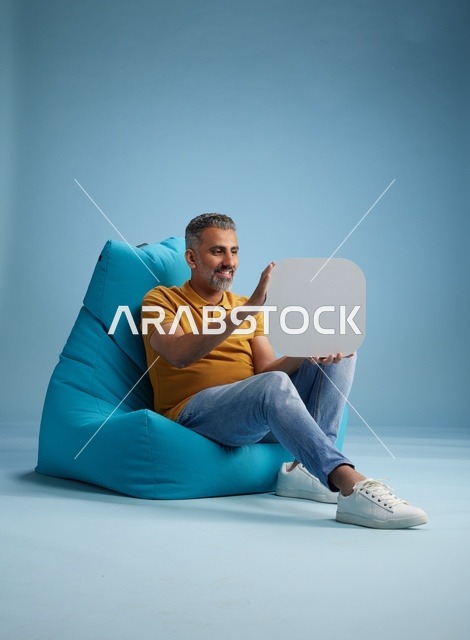 رجل سعودي يحمل لوحة موك أب فارغة على كرسي