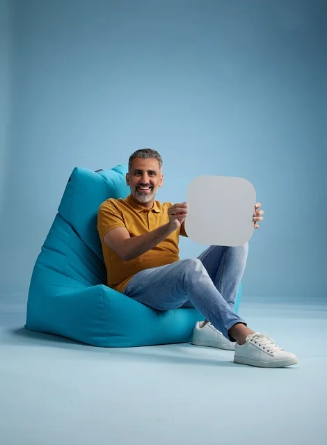 Saudi Man Sitting on Beanbag Holding Mockup Board