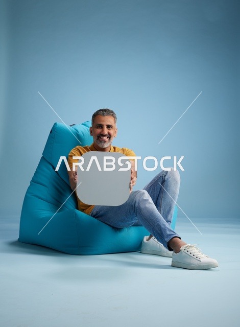 رجل سعودي يحمل لوحة فارغة على مقعد أزرق
