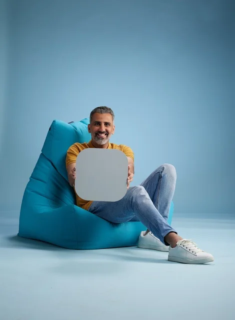 رجل سعودي يحمل لوحة فارغة على مقعد أزرق