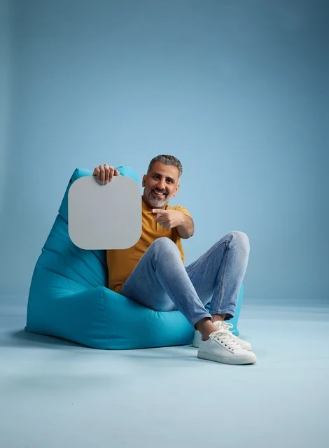 رجل سعودي يحمل لوحة موك أب فارغة على مقعد محشو