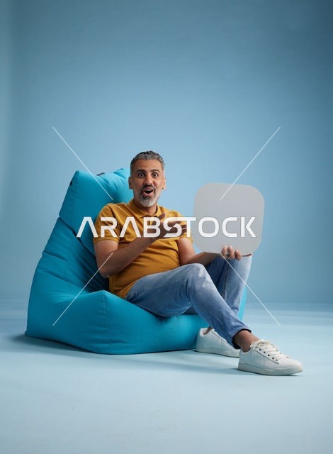 رجل سعودي يحمل لوحة موك أب فارغة بخلفية زرقاء