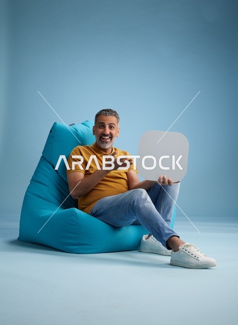 رجل سعودي يحمل لوحة موك أب فارغة بخلفية زرقاء