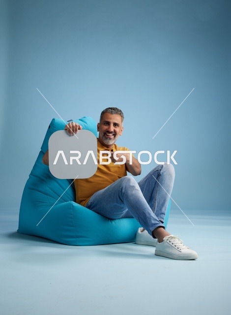 رجل سعودي يحمل لوحة موك أب بيضاء فارغة في استوديو