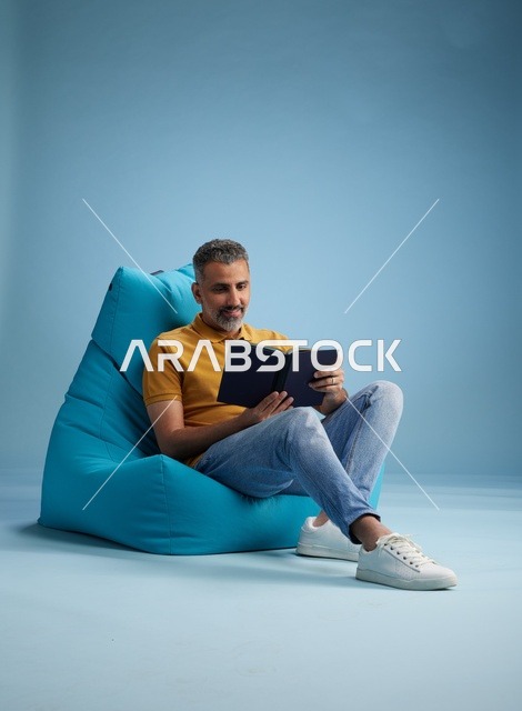 رجل سعودي يقرأ كتاباً على كرسي مريح