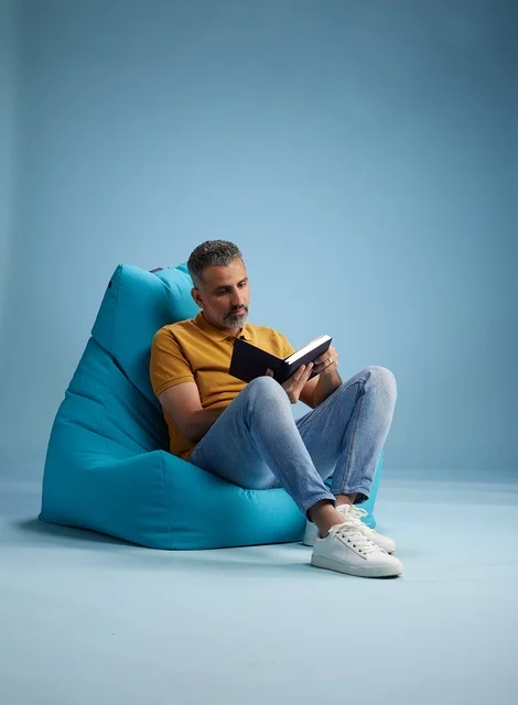رجل سعودي يقرأ كتاباً في خلفية استوديو زرقاء