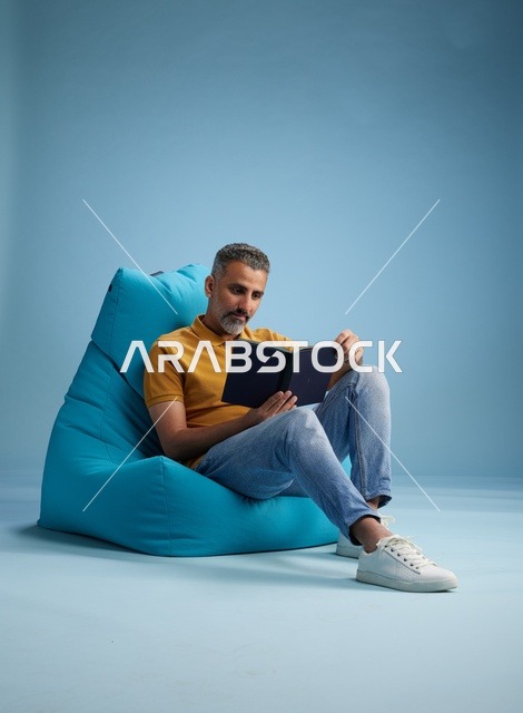 رجل سعودي يقرأ كتاباً على كرسي بين باج