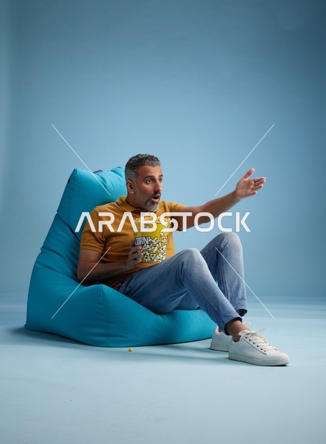 رجل سعودي يأكل الفشار على كرسي بين باج في استوديو