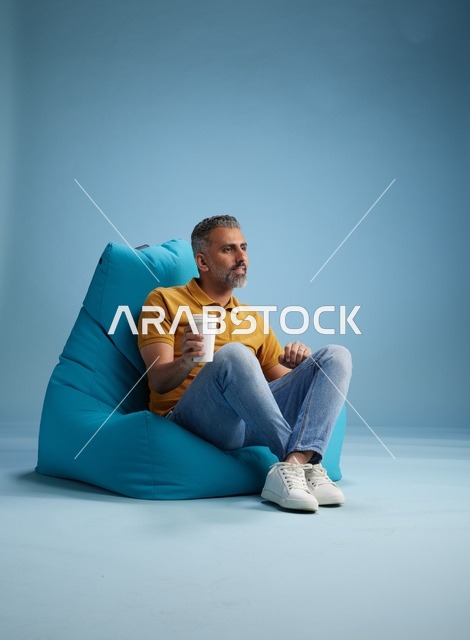 رجل سعودي يسترخي على مقعد مريح مع كوب قهوة