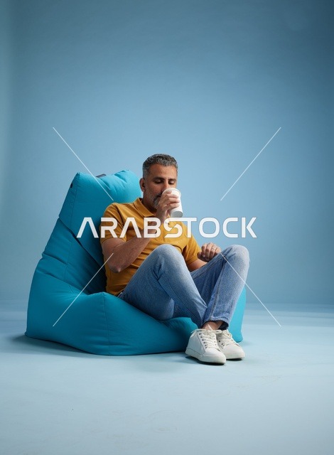 رجل سعودي يسترخي على كرسي بين باج مع قهوة