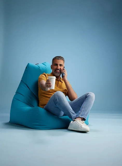 Saudi Man Relaxing on Beanbag with Coffee and Phone