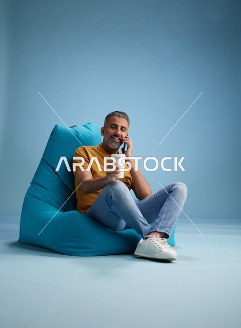 رجل سعودي يتحدث بالهاتف مع كوب قهوة